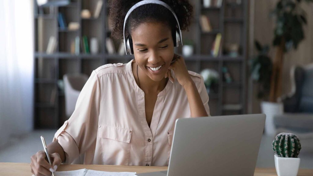 a woman wearing headphones and looking at a laptop