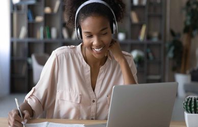 a woman wearing headphones and looking at a laptop